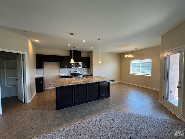 kitchen featuring a notable chandelier, appliances with stainless steel finishes, a sink, light stone counters, and backsplash