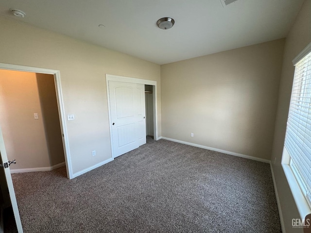 unfurnished bedroom with carpet floors, baseboards, and a closet
