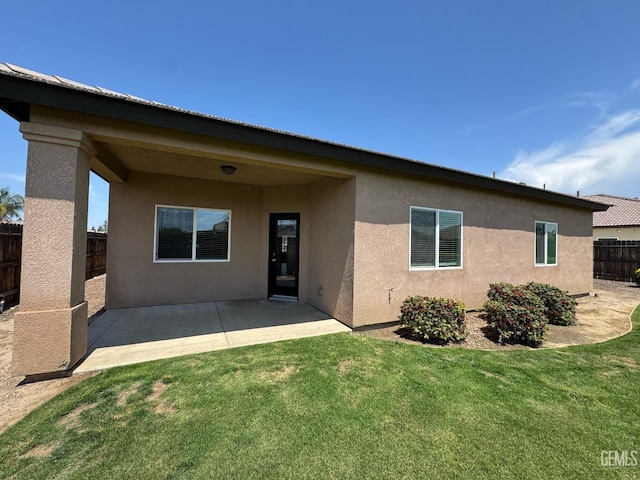 view of front of property with stucco siding, a front lawn, fence private yard, and a patio area