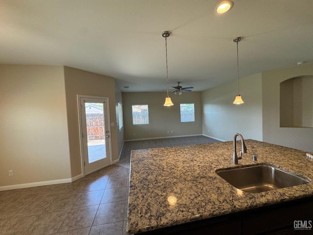 kitchen with a ceiling fan, a sink, baseboards, tile patterned floors, and stone counters