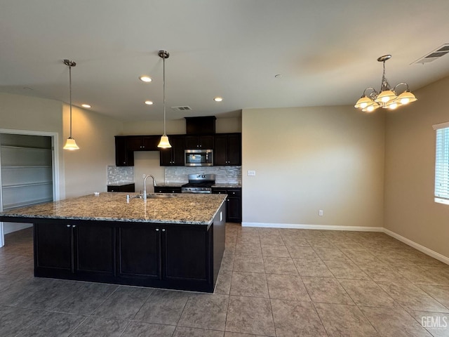 kitchen with light stone counters, a sink, stainless steel appliances, tasteful backsplash, and visible vents