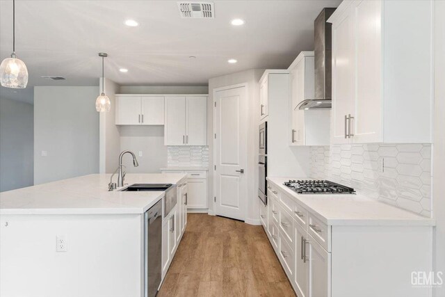 11001 Arundel Way, Bakersfield, CA 93311 - kitchen with stainless steel appliances, wall chimney exhaust hood, white cabinets, a kitchen island with sink, and recessed lighting
