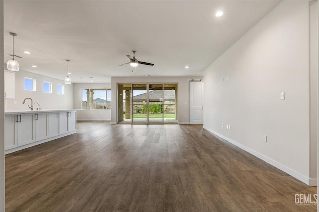 11001 Arundel Way, Bakersfield, CA 93311 - unfurnished living room with baseboards, dark wood-style flooring, recessed lighting, ceiling fan, and a sink