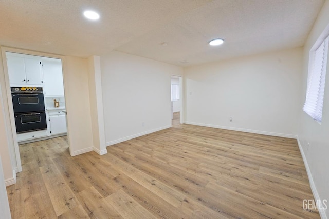 unfurnished room featuring light wood-style flooring, baseboards, and recessed lighting