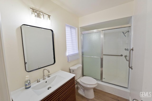 bathroom with vanity, wood finished floors, a shower stall, and toilet