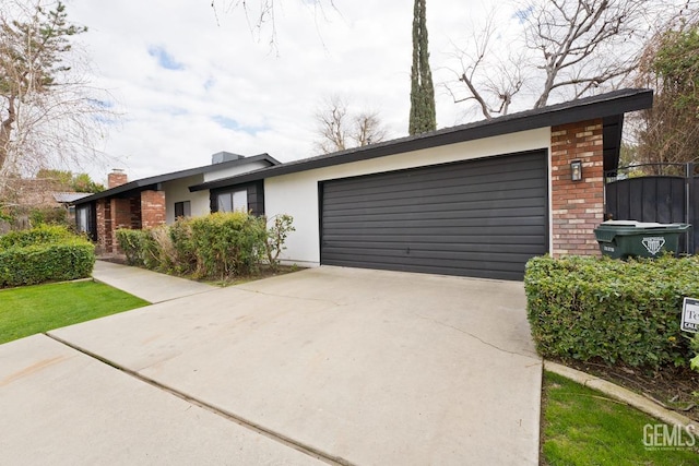 view of front of property with an attached garage, brick siding, driveway, and stucco siding