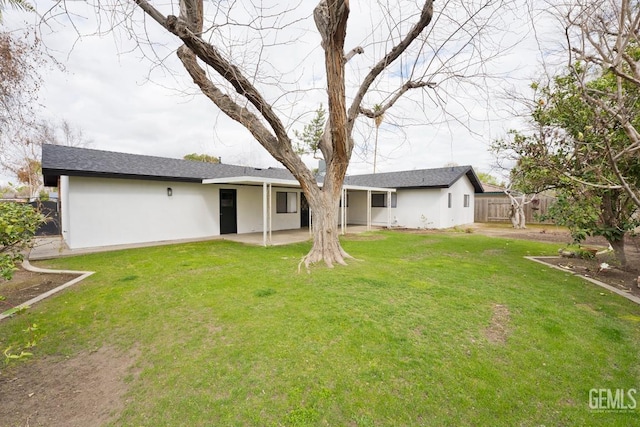 back of property featuring stucco siding, a patio area, fence, and a yard