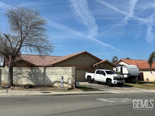 view of front facade featuring a garage, driveway, a tiled roof, and stucco siding