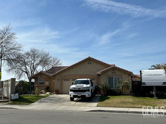 view of front of home featuring an attached garage, driveway, a tiled roof, stucco siding, and a front yard