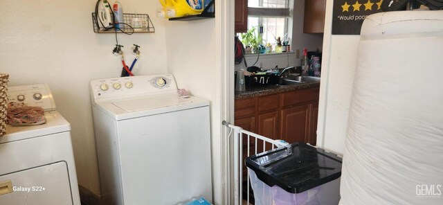 clothes washing area with independent washer and dryer and a sink