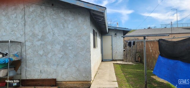 view of property exterior with stucco siding and fence