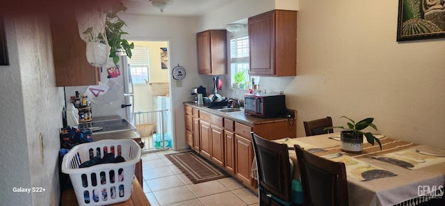 kitchen with brown cabinetry, light tile patterned floors, and a sink