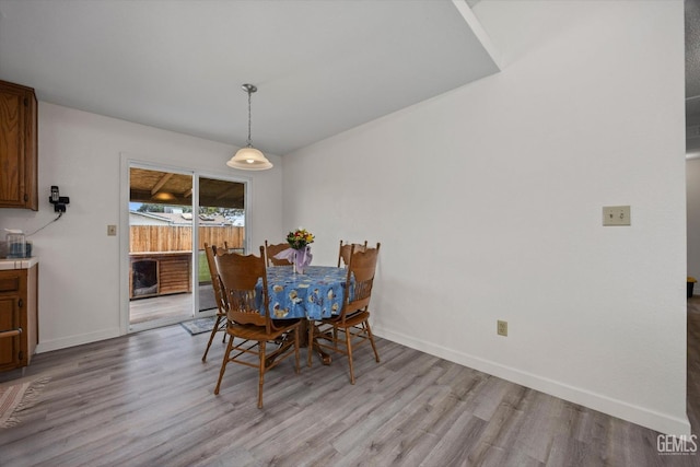 dining space with light wood-type flooring and baseboards