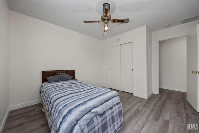 bedroom featuring a closet, baseboards, wood finished floors, and visible vents