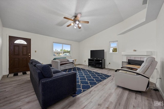 living area with a ceiling fan, wood finished floors, a wealth of natural light, and a fireplace