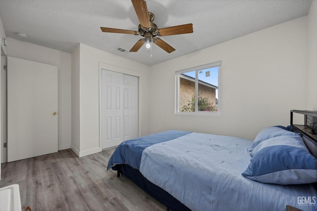 bedroom featuring a ceiling fan, baseboards, wood finished floors, visible vents, and a closet