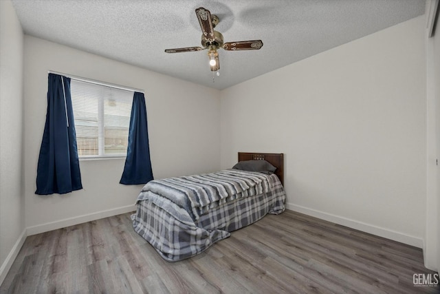 bedroom with baseboards, a textured ceiling, and wood finished floors