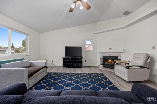living area featuring visible vents, light wood-style floors, baseboards, ceiling fan, and vaulted ceiling