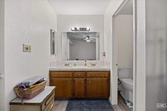 full bath with a sink, double vanity, and wood finished floors