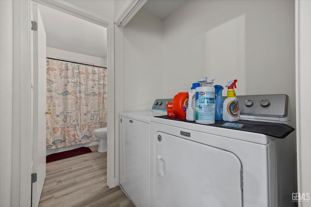 clothes washing area with separate washer and dryer and light wood-type flooring