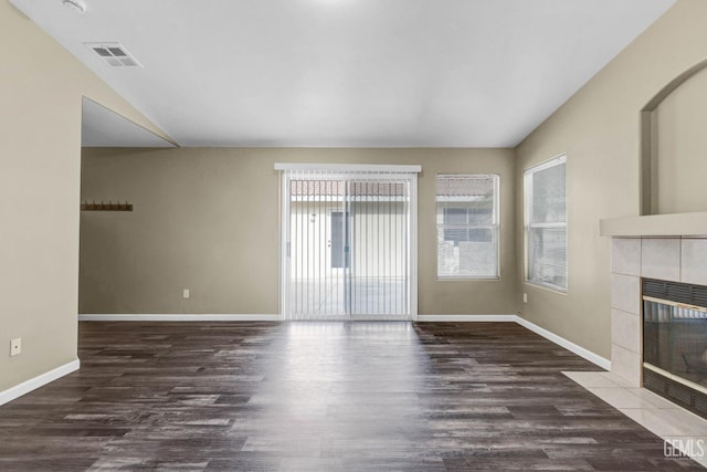 unfurnished living room featuring visible vents, a tiled fireplace, vaulted ceiling, wood finished floors, and baseboards