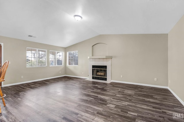 unfurnished living room with dark wood-style floors, lofted ceiling, visible vents, a tile fireplace, and baseboards