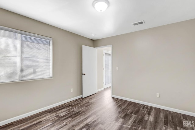 spare room with plenty of natural light, wood finished floors, visible vents, and baseboards