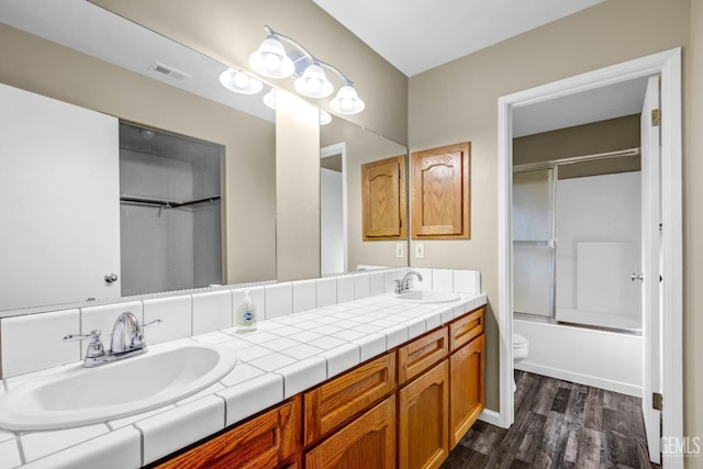 bathroom with toilet, wood finished floors, a sink, and visible vents