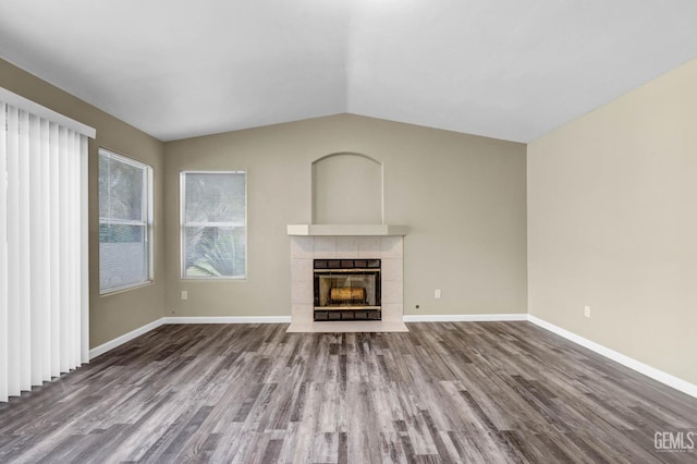 unfurnished living room with a tile fireplace, lofted ceiling, baseboards, and wood finished floors