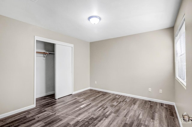 unfurnished bedroom featuring a closet, baseboards, and wood finished floors