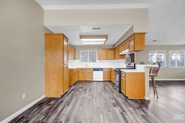 kitchen featuring tasteful backsplash, visible vents, dishwasher, a peninsula, and stainless steel range with gas stovetop