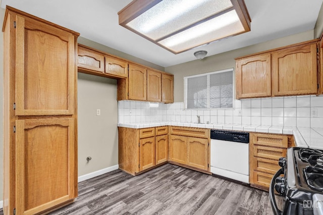 kitchen featuring black range with gas cooktop, tile counters, dishwasher, and backsplash