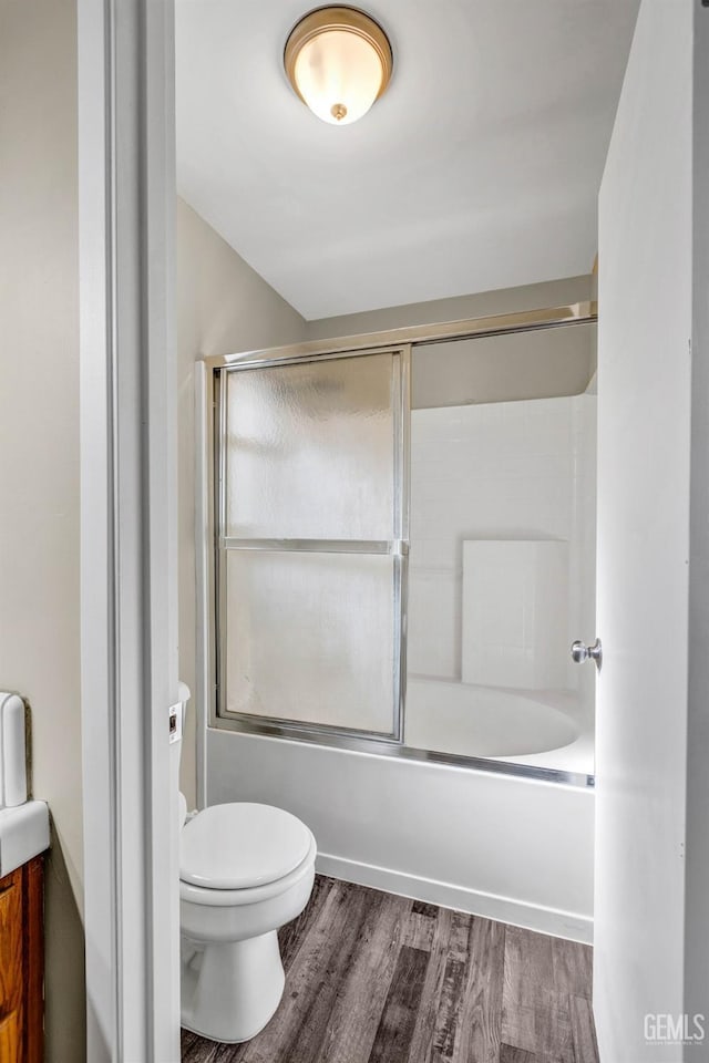 bathroom featuring enclosed tub / shower combo, wood finished floors, and toilet