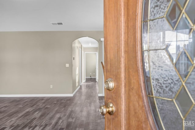 interior space with arched walkways, visible vents, baseboards, and wood finished floors