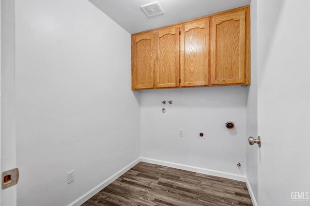 clothes washing area featuring hookup for a gas dryer, dark wood-type flooring, visible vents, baseboards, and cabinet space