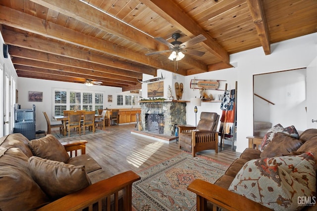 living area featuring a fireplace, wood finished floors, wood ceiling, a ceiling fan, and beam ceiling