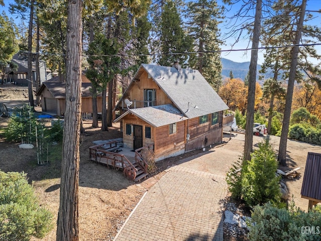 view of home's exterior featuring a shingled roof, decorative driveway, and a deck with mountain view