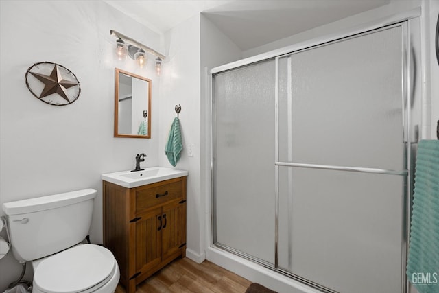 bathroom with a stall shower, vanity, toilet, and wood finished floors