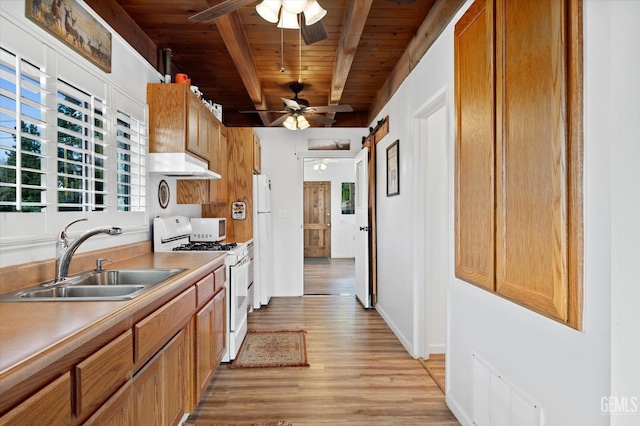 kitchen featuring light wood-style flooring, a ceiling fan, a sink, white appliances, and beamed ceiling