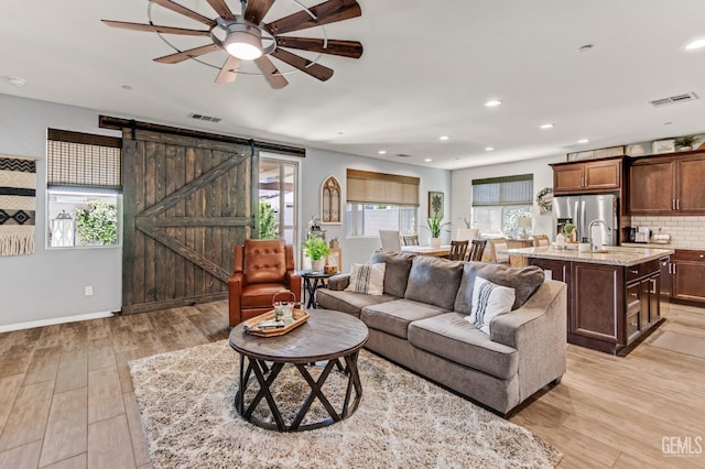 living room featuring visible vents, ceiling fan, recessed lighting, a barn door, and light wood finished floors