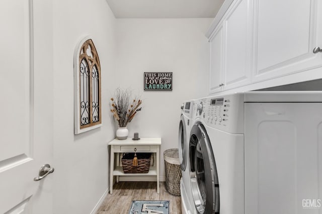 laundry room with baseboards, cabinet space, light wood finished floors, and washing machine and dryer