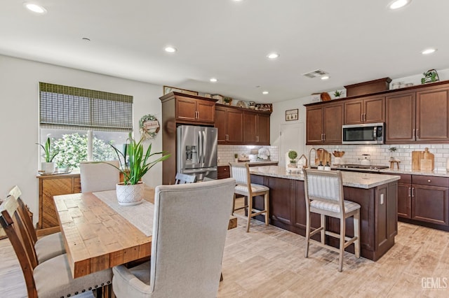 kitchen with visible vents, an island with sink, recessed lighting, tasteful backsplash, and stainless steel appliances