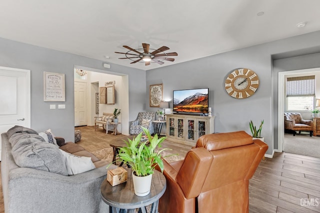 living area featuring baseboards, a ceiling fan, and wood finished floors
