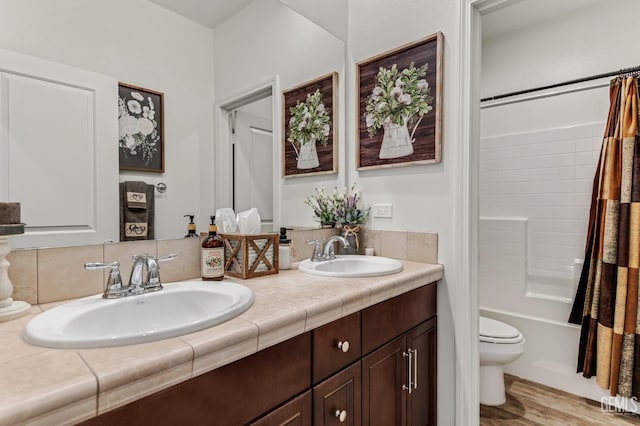 bathroom with double vanity, toilet, a sink, and wood finished floors