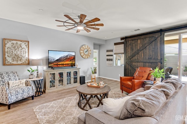 living area featuring visible vents, a barn door, wood finished floors, and a wealth of natural light