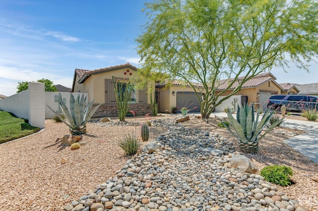 view of front of home with an attached garage, stucco siding, a tile roof, and fence