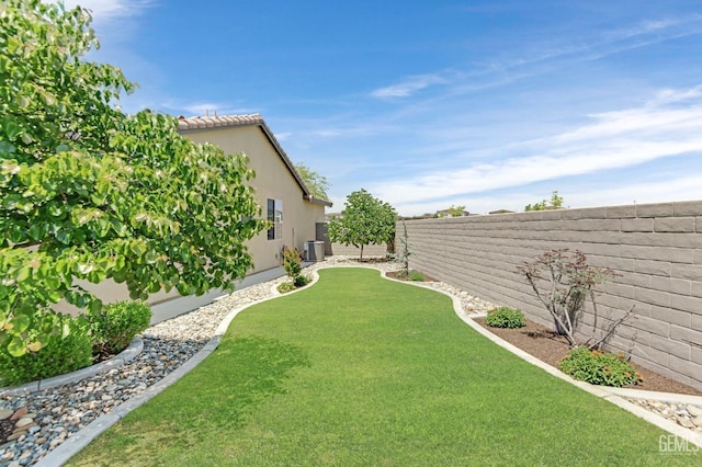view of yard with a fenced backyard and central AC unit
