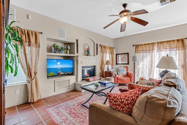 tiled living room featuring ceiling fan and a brick fireplace