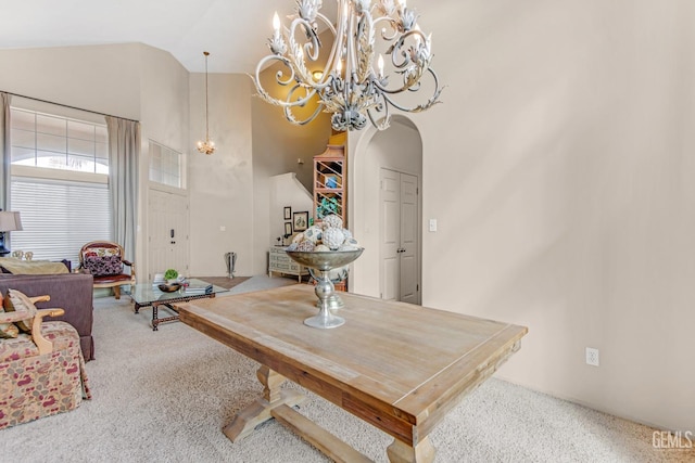 dining space with carpet flooring, a chandelier, and high vaulted ceiling