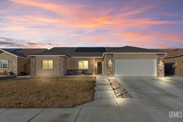 prairie-style home featuring a lawn, solar panels, and a garage